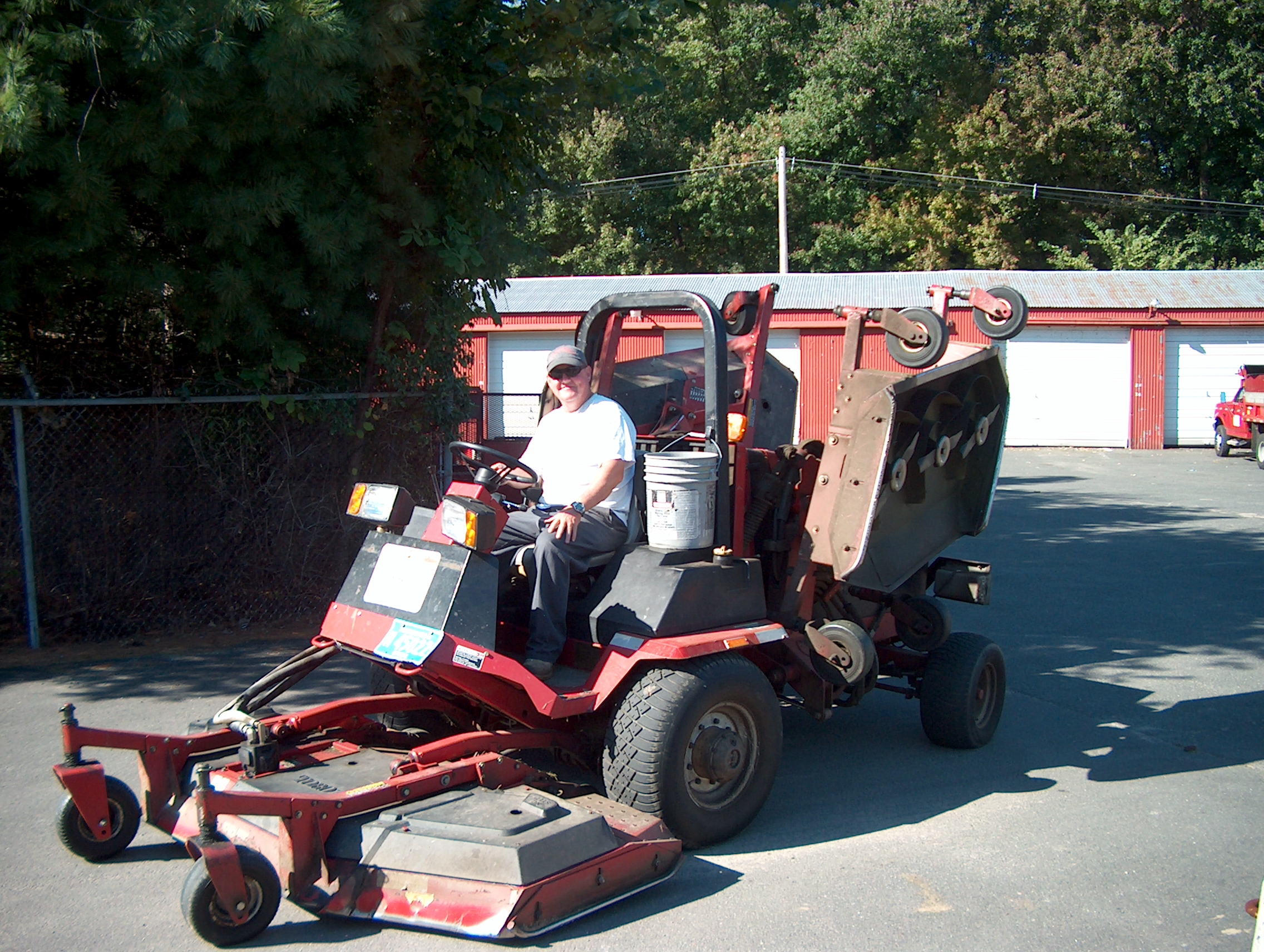 DPW employee sitting on riding lawnmower smiling
